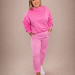 Bluza damska over basic różowa PatiStyle. Świetna, wygodna luźna gładka bluza z przeszyciem na plecach w pięknym kolorze różowym. Spodnie damskie cygaretki z kwiatem różowe PatiStyle. Wgodne spodnie z gumką w pasie oraz ozdobnym paskiem z kwiatem.