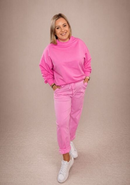 Bluza damska over basic różowa PatiStyle. Świetna, wygodna luźna gładka bluza z przeszyciem na plecach w pięknym kolorze różowym. Spodnie damskie cygaretki z kwiatem różowe PatiStyle. Wgodne spodnie z gumką w pasie oraz ozdobnym paskiem z kwiatem.