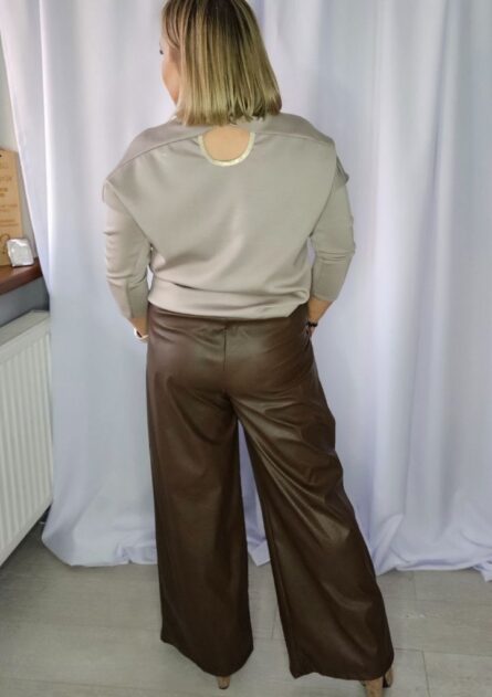 Spodnie damskie kuloty z zakładkami brązowe PatiStyle. Spodnie szerokie z ekoskóry, z gumką w pasie i ozdobnym paskiem w zestawie Bluzka damska z ozdobną broszką latte PatiStyle. Elegancka bluzka z rękawem 3/4, elegancką broszką oraz delikatnym wycięciem na plecach.